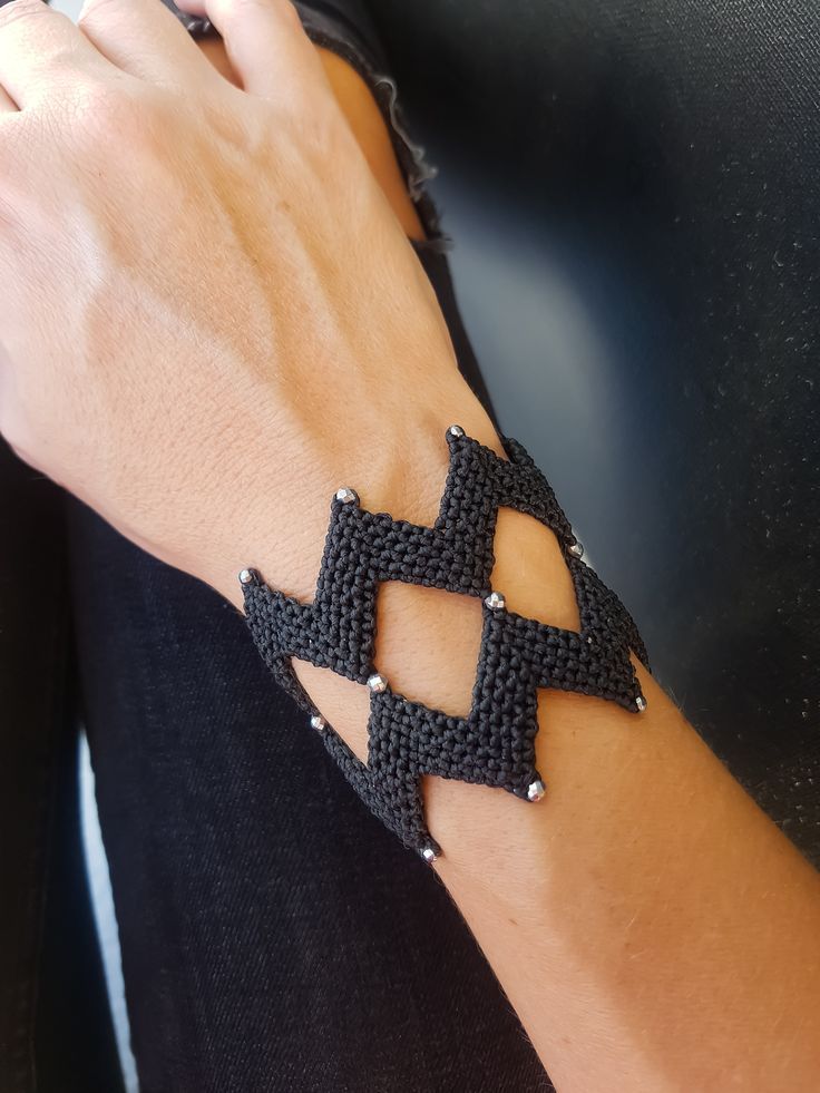 a woman's arm with a black crochet bracelet on it