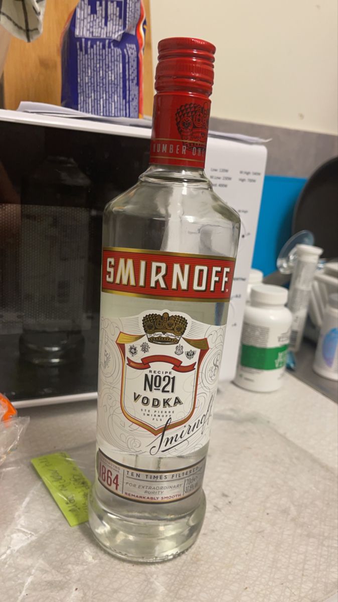 a bottle of smirnoff vodka sitting on top of a counter next to a microwave