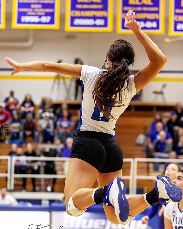 a woman jumping in the air to hit a volleyball