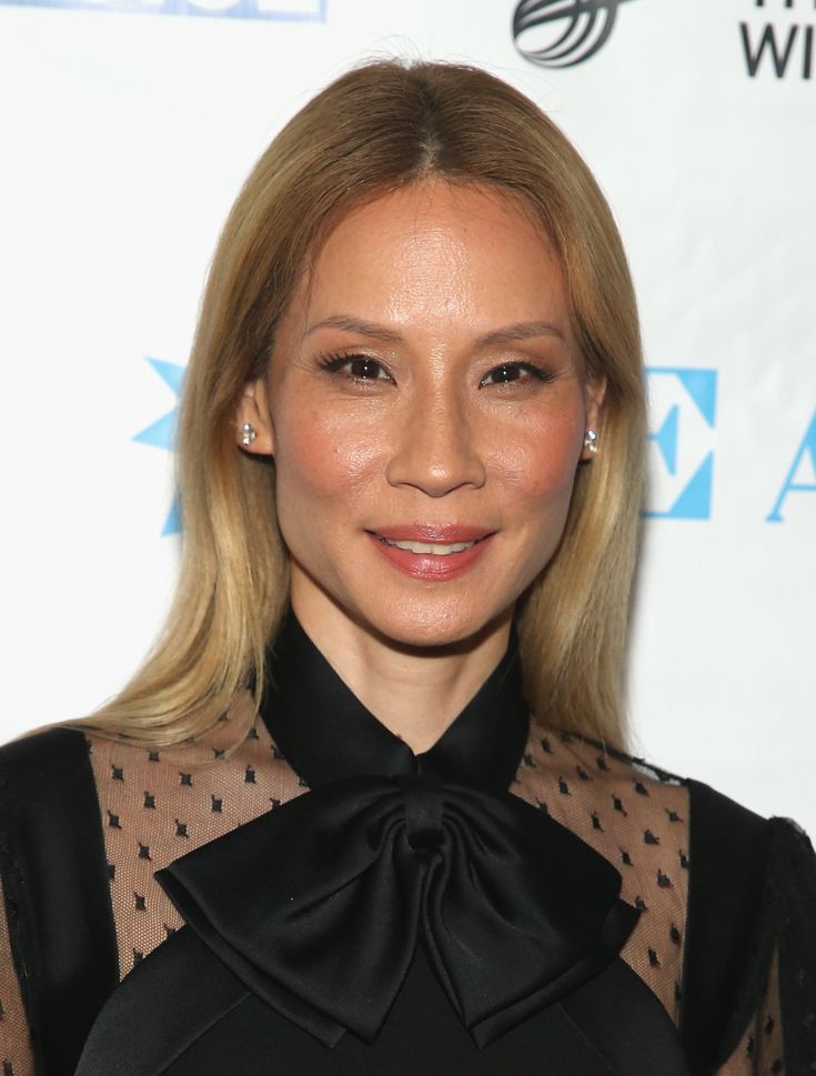 a woman with long blonde hair wearing a black shirt and bow tie at an event