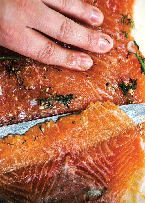 a person is cutting up some fish on a plate with a knife and seasoning