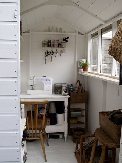 a small room with white walls and wooden furniture in the corner, including a sewing machine