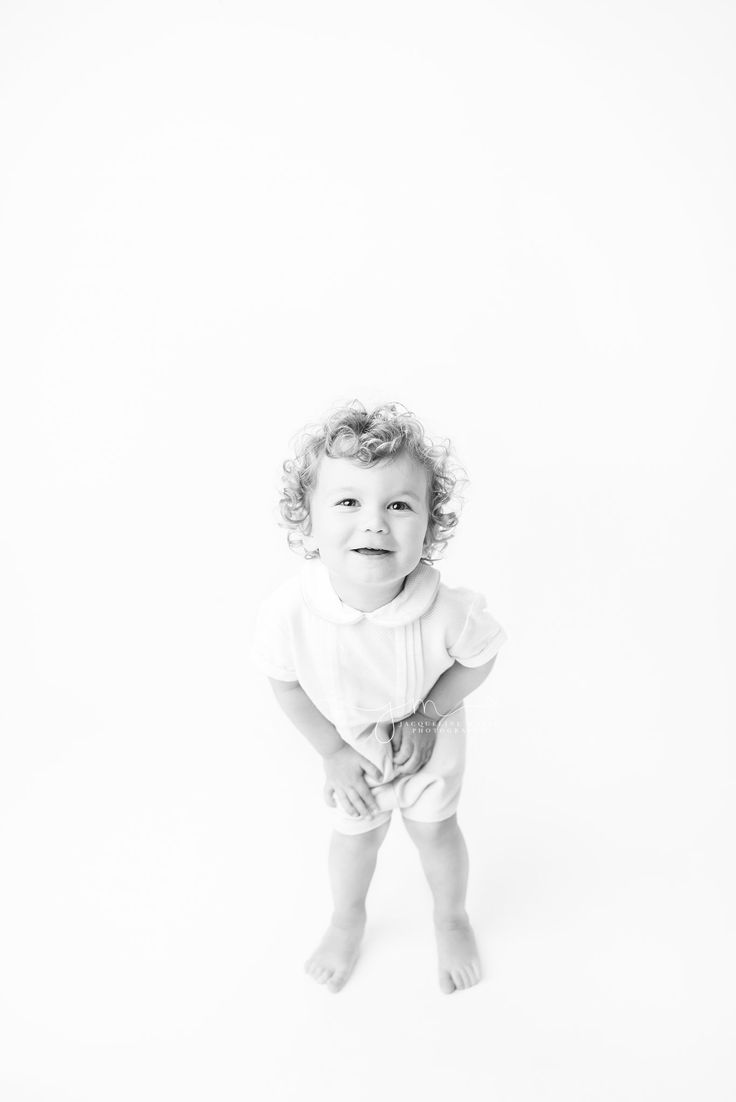 a black and white photo of a toddler in diapers smiling at the camera