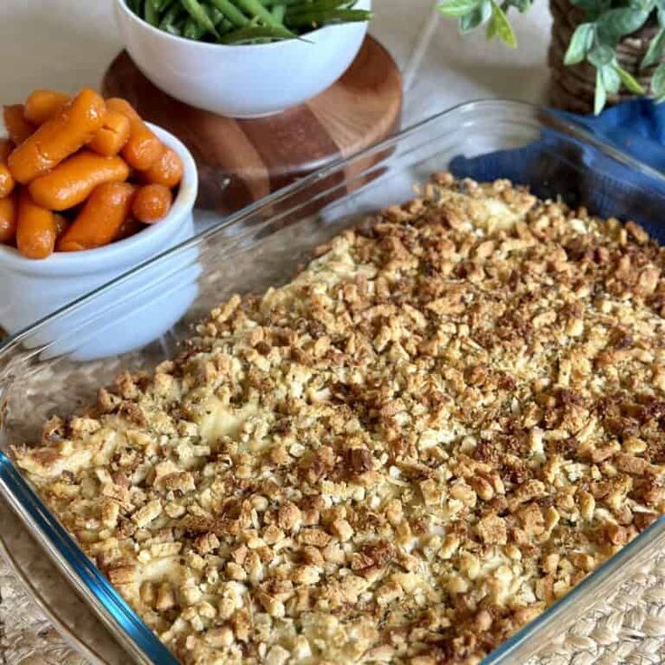 a casserole dish with carrots and other vegetables in bowls on the side