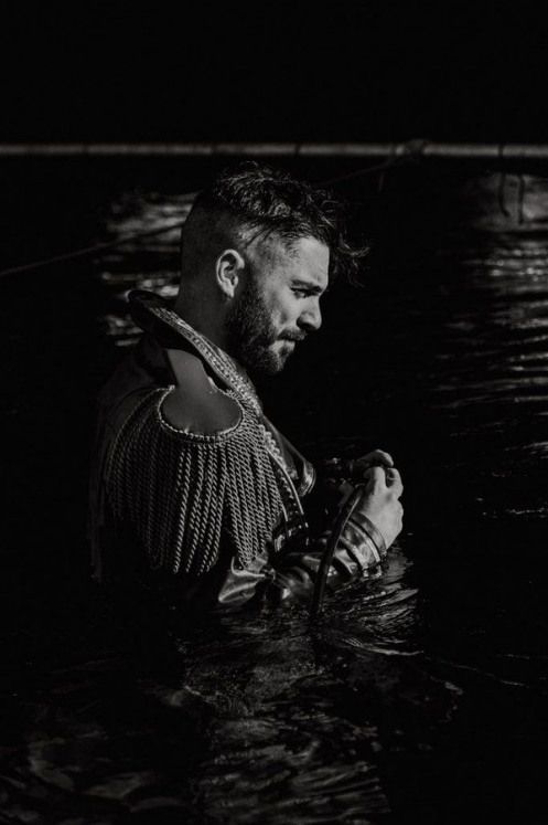 a man is standing in the water with his hands on his chest and looking at something