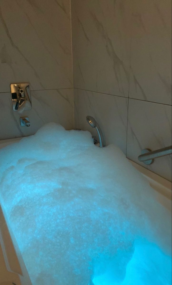 a bathtub filled with water next to a wall mounted faucet and shower head