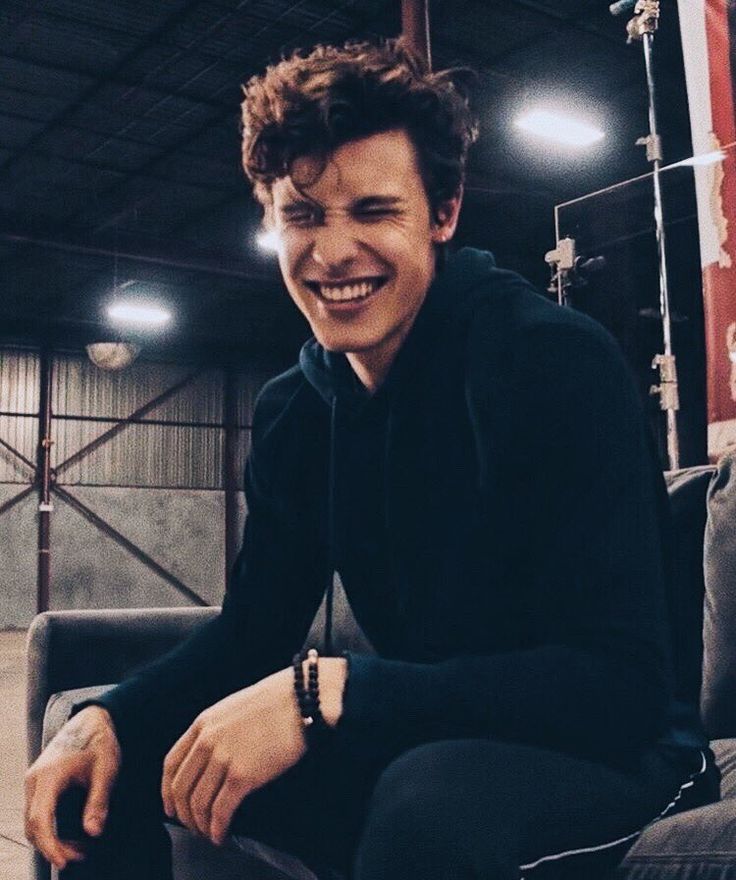 a smiling young man sitting on top of a couch