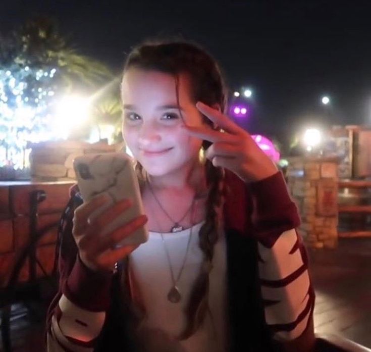 a girl is holding her cell phone up to her face and smiling at the camera