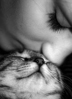 a person kissing a cat with their eyes closed