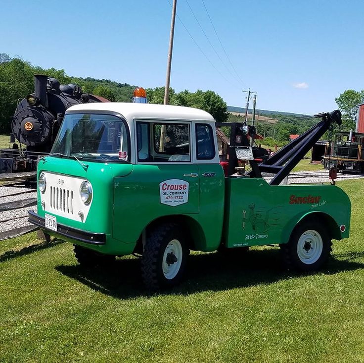 an old truck is parked in the grass near a train track and some other vehicles