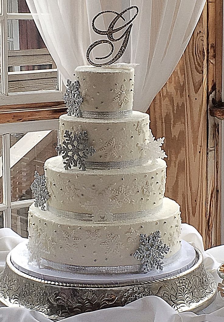 a three tiered wedding cake sitting on top of a silver platter next to a window