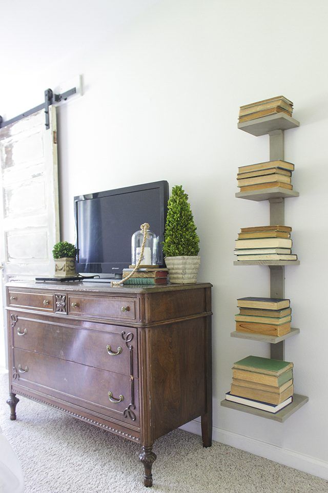 a tv sitting on top of a wooden dresser next to a book shelf filled with books