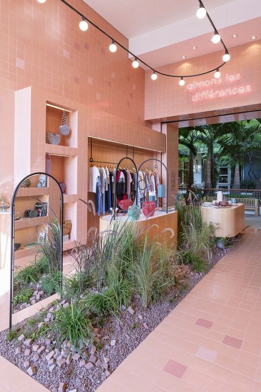 the inside of a clothing store with lots of plants