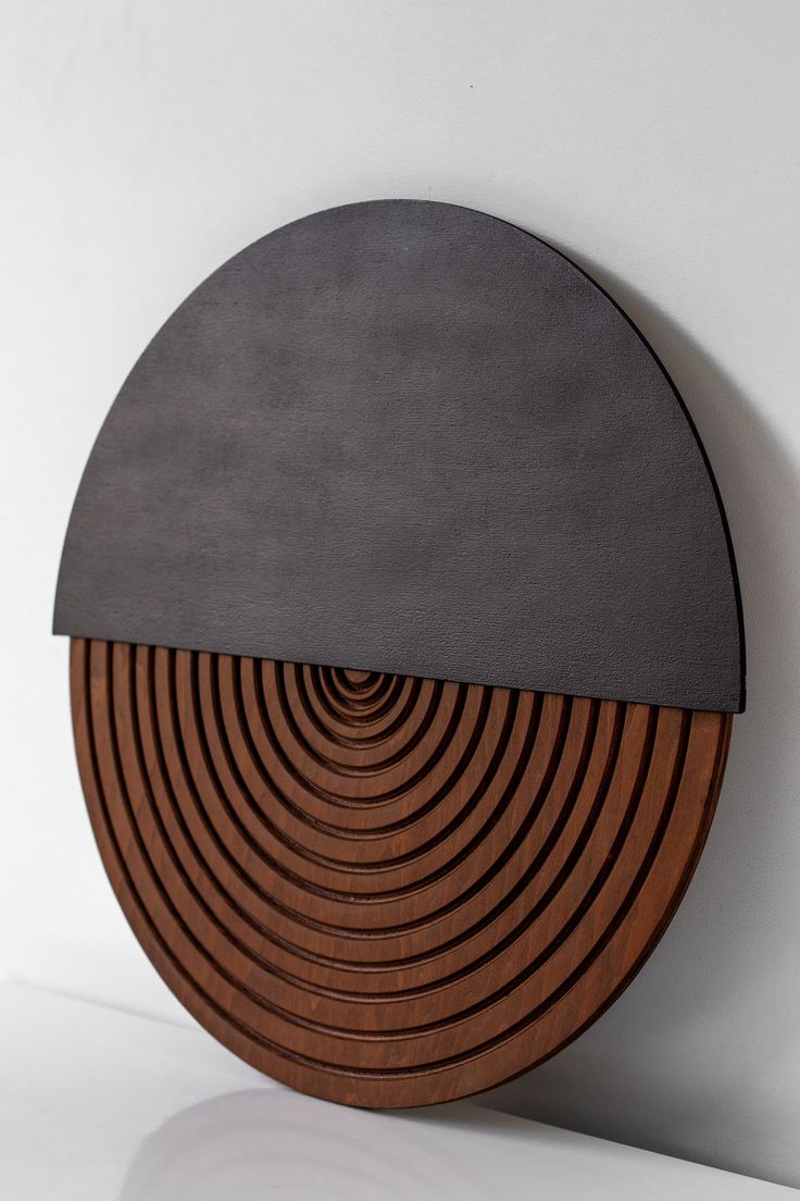 a circular wooden object with black and brown lines on the top, against a white wall