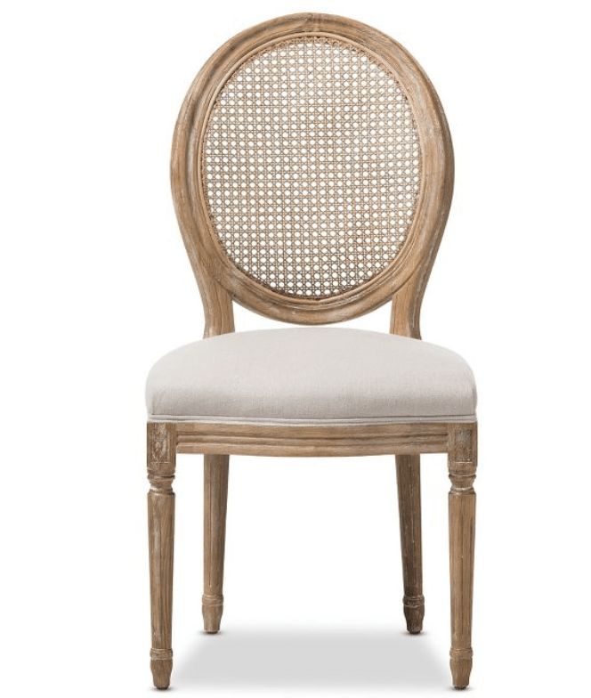 the back side of a wooden chair with a white upholstered seat and caned back