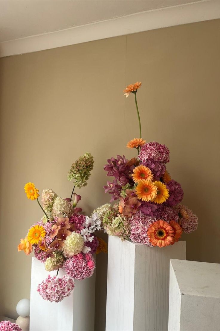 two white vases with colorful flowers in them