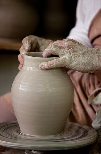 a person holding a clay pot with their hands on it