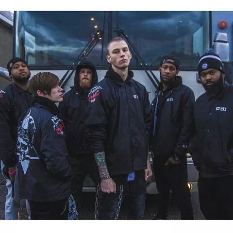 a group of young men standing next to each other in front of a white bus