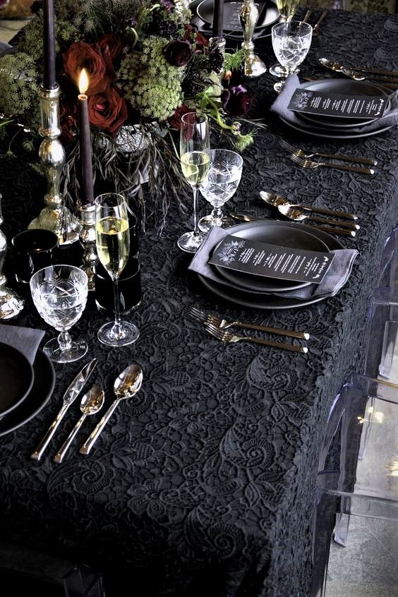 the table is set with black plates, silverware and candles for an elegant dinner