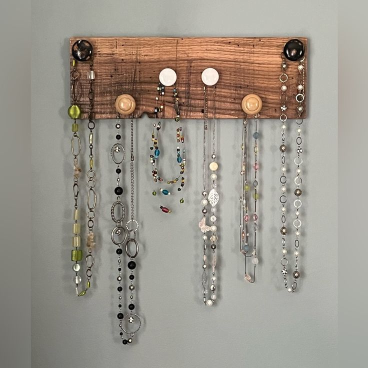 a wooden rack with lots of necklaces hanging from it's sides on a wall