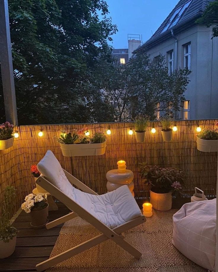 a small balcony with potted plants and lights on the wall, along with a white lawn chair