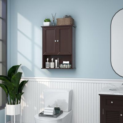 a white toilet sitting next to a sink in a bathroom under a mirror and a potted plant