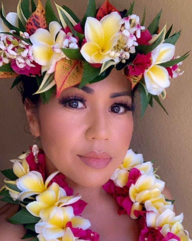 a woman with flowers in her hair wearing a lei and flower crown on her head