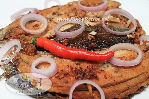 a white plate topped with meat and onions on top of it next to a red pepper