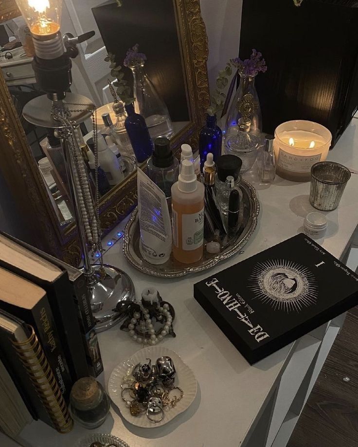 a table topped with lots of bottles and candles next to an open book on top of a table