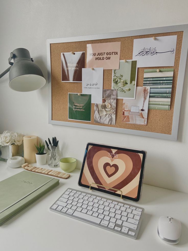 a desk with a computer, keyboard and mouse next to a cork board that has pictures on it