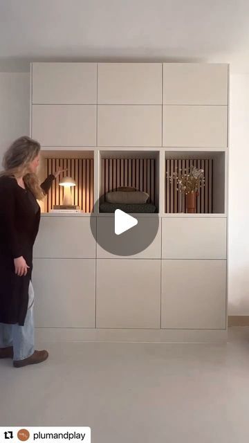 a woman standing in front of a white wall with built - in bookshelves