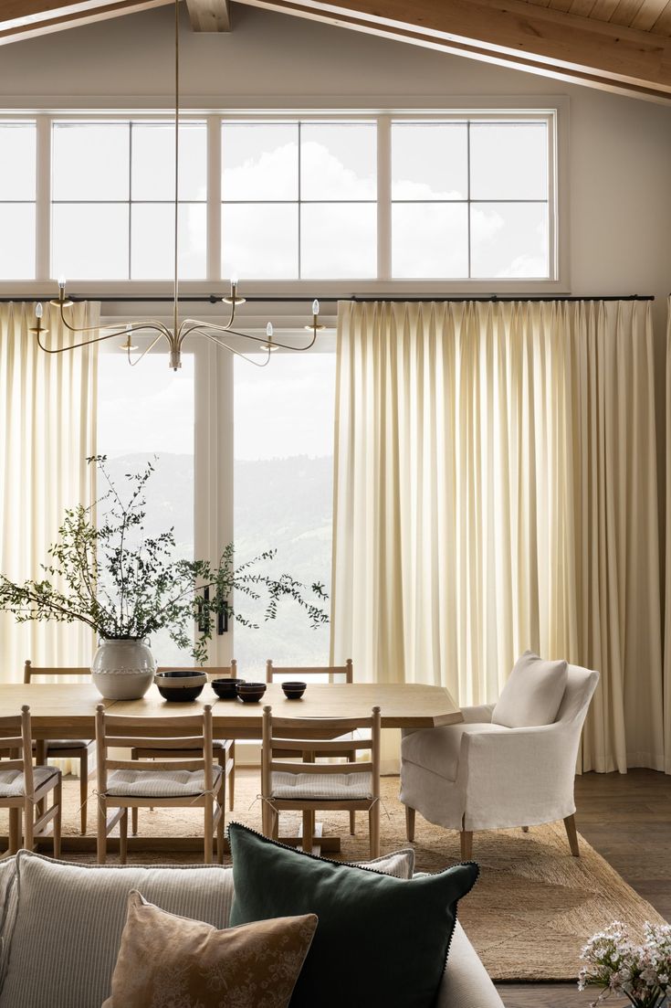 a living room filled with furniture and a dining table next to a window covered in curtains