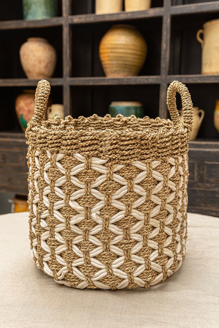 a woven basket sitting on top of a table next to shelves filled with vases