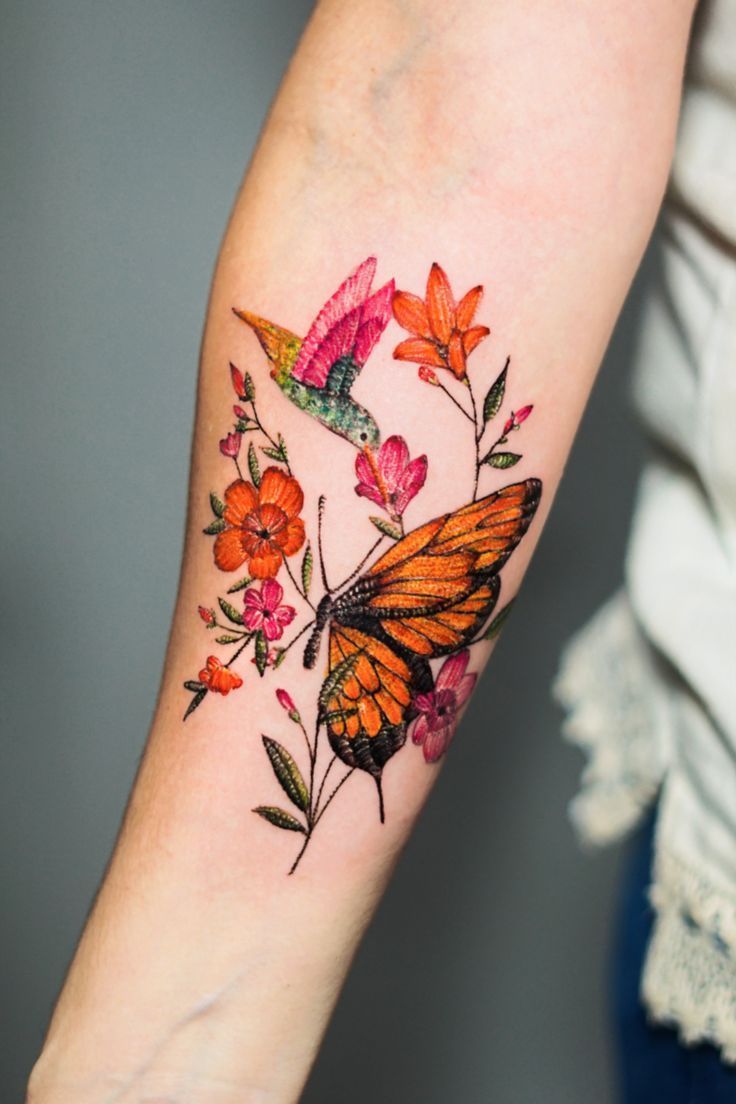 a woman's arm with an orange butterfly and flowers on it