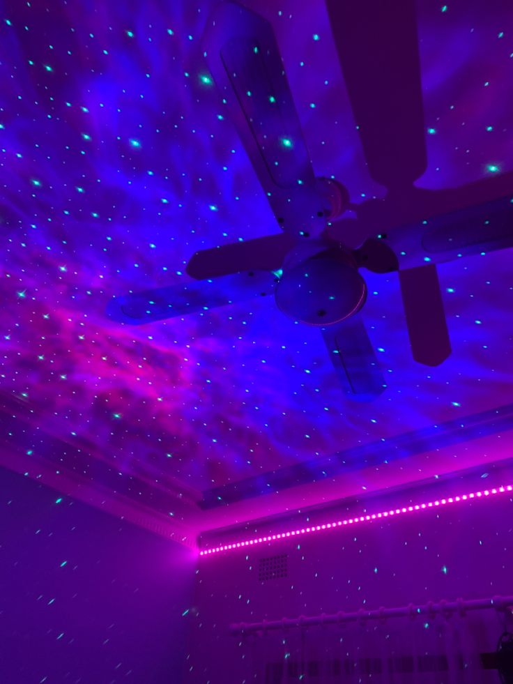 a ceiling with purple and blue lights in the middle of it is lit up by two remote controls