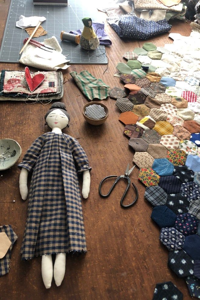 a doll is laying on the floor next to many pieces of fabric and scissors,