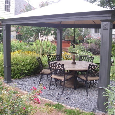 a patio with a table and chairs under a gazebo in the middle of a garden