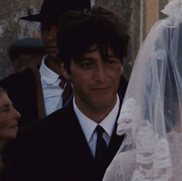 a man in a suit and tie standing next to a woman wearing a wedding veil