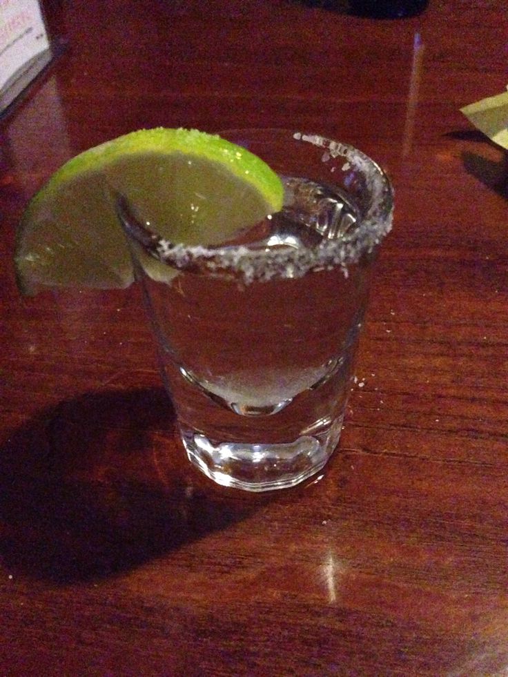 a close up of a drink on a table with a slice of lime in it