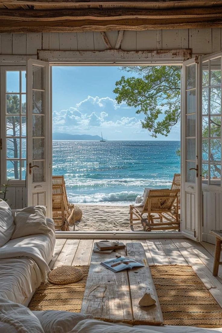 a living room filled with furniture and an open door leading to the water's edge