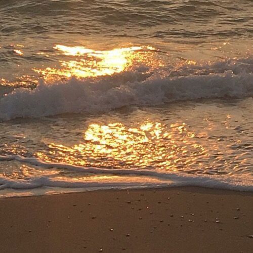 the sun is setting over the water at the beach