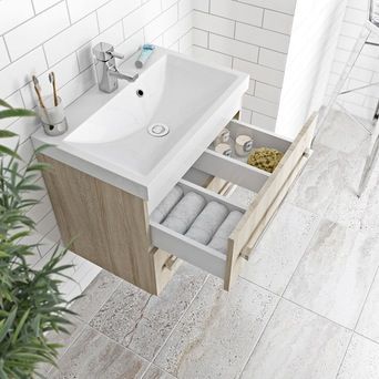 a bathroom sink sitting under a mirror next to a plant