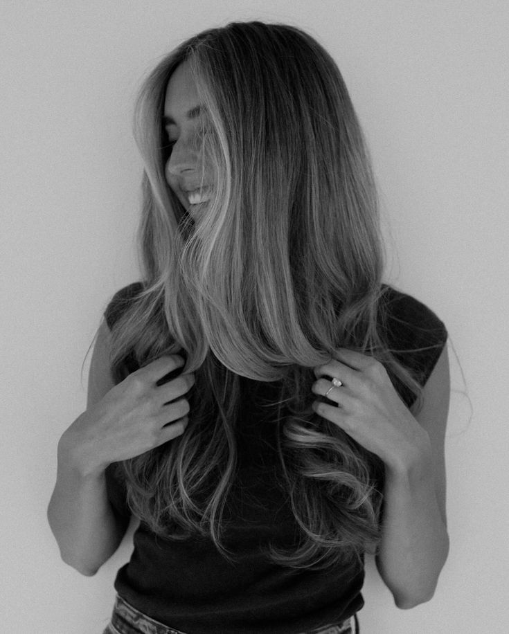 a woman with long hair standing in front of a white wall