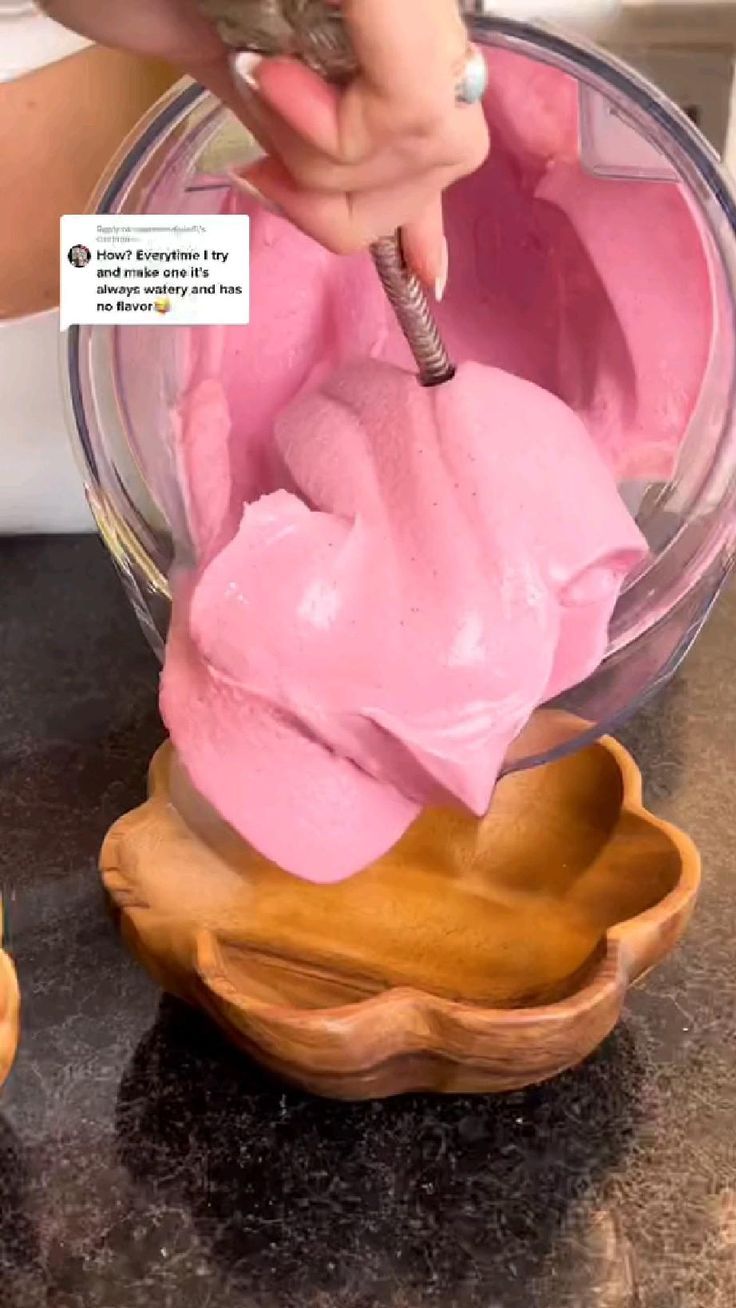 a person is mixing pink icing in a bowl