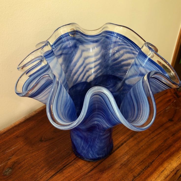 a blue glass vase sitting on top of a wooden table