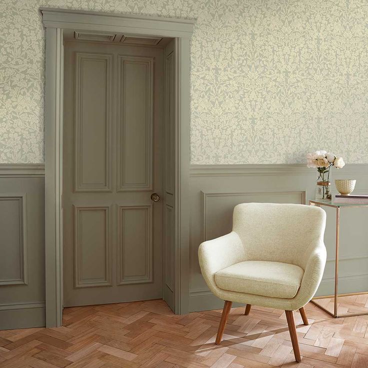 a white chair sitting in front of a door next to a table with flowers on it