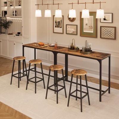 a dining room table with four stools in front of it and pictures on the wall