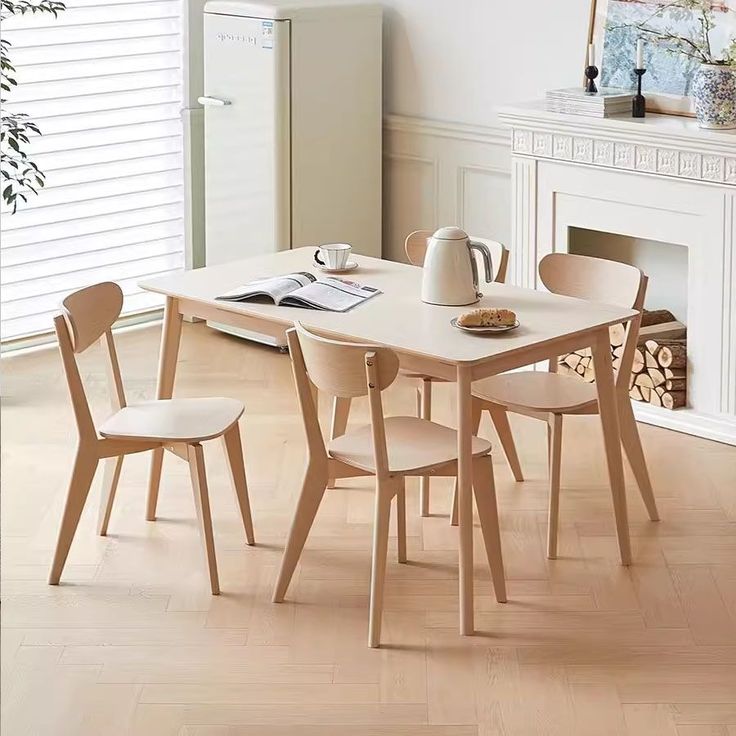 a dining table with four chairs in front of a fire place and a white refrigerator