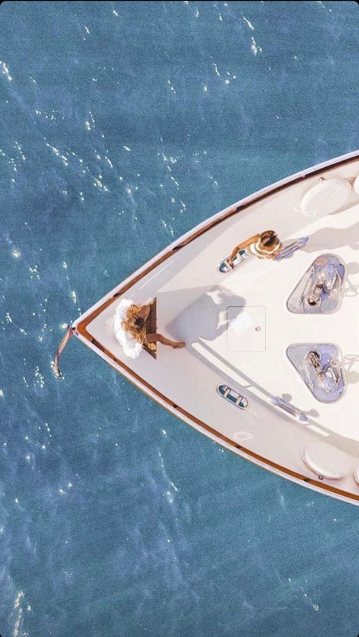 an aerial view of a white boat in the ocean with people on it's deck