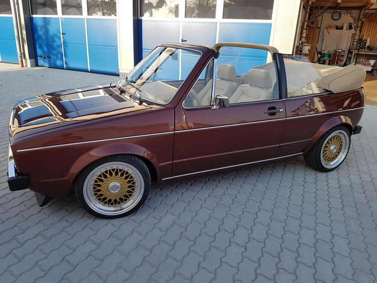 a brown car parked in front of a building with its doors open and the roof down